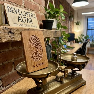 Eine antique Waage mit einem Holzschild und Pflanzen im Hintergrund in einem Büro.